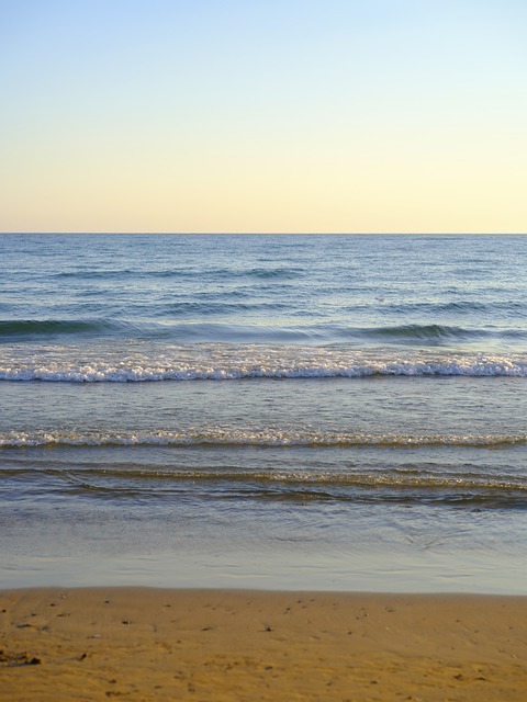A closeup scene of the beach and calm beach waves during the day.